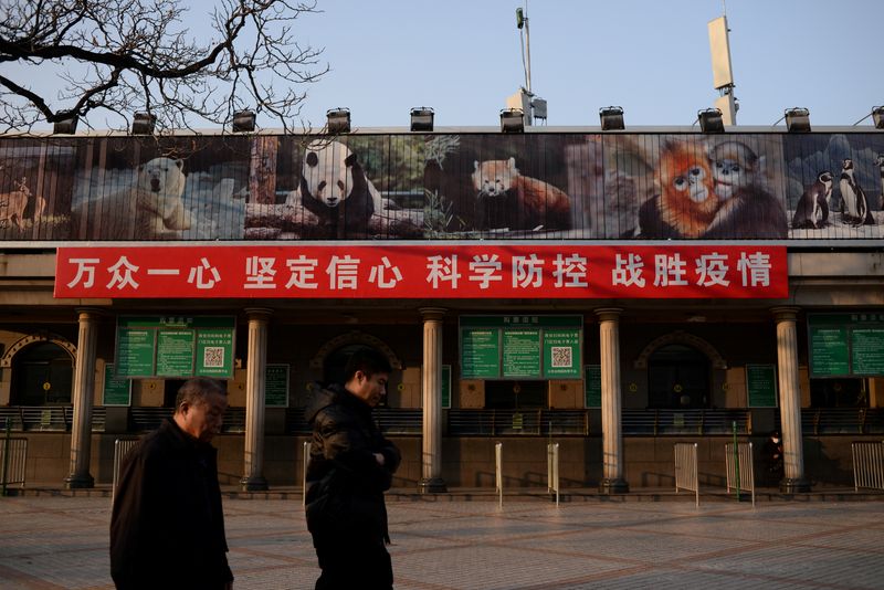 &copy; Reuters. FOTO DE ARCHIVO: Unas personas pasan junto a una pancarta colgada en la taquilla del zoo de Pekín, cerrado tras un brote del COVID, en Pekín, China, 10 de febrero de 2020. REUTERS/Tingshu Wang