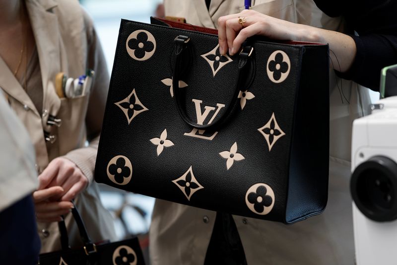 © Reuters. FILE PHOTO: Employees hold handbags in a workshop at the Atelier Louis Vuitton in Vendome, France, February 22, 2022. REUTERS/Benoit Tessier