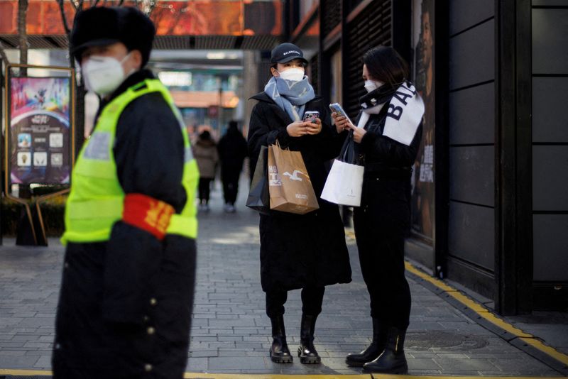 &copy; Reuters. FILE PHOTO: Women with shopping bags stand in a street as China returns to work despite continuing coronavirus disease (COVID-19) outbreaks in Beijing, China, January 3, 2023. REUTERS/Thomas Peter