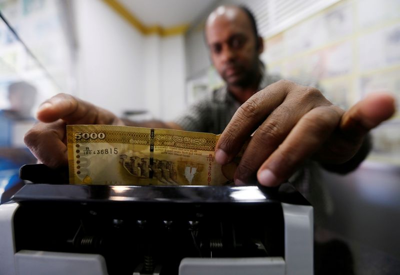 &copy; Reuters. FILE PHOTO: A man counts Sri Lankan rupees in a note counting machine at a money exchange counter in Colombo, Sri Lanka September 7, 2018. REUTERS/Dinuka Liyanawatte