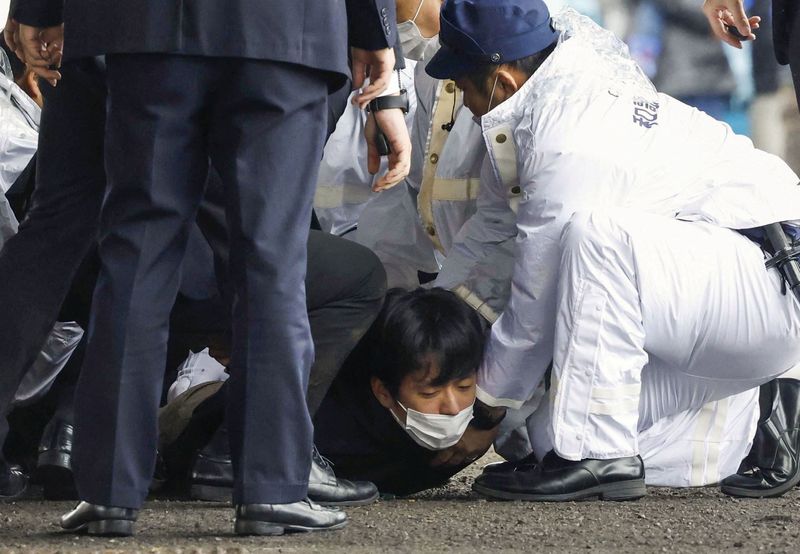 © Reuters. A man, believed to be a suspect who threw a pipe-like object near Japanese Prime Minister Fumio Kishida during his outdoor speech, is held by police officers at Saikazaki fishing port in Wakayama, Wakayama Prefecture, south-western Japan April 15, 2023, in this photo released by Kyodo. Mandatory credit Kyodo via REUTERS 