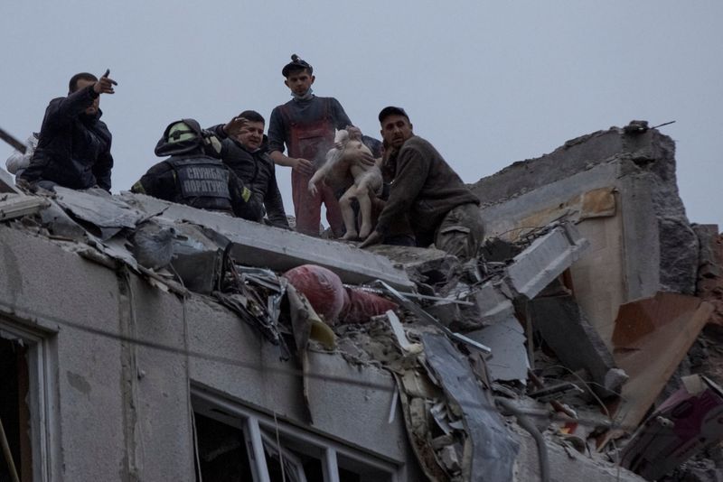 © Reuters. Emergency workers and volunteers rescue a child at a site of an apartment building damaged by a Russian military strike, amid Russia's attack on Ukraine, in Sloviansk, Donetsk region, Ukraine April 14, 2023.  REUTERS/Anna Kudriavtseva