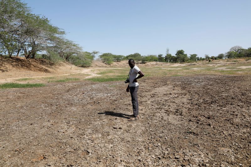 &copy; Reuters. FILE PHOTO: Famine Early Warning System Network in Africa (FEWS NET) scientist Chris Shitote examines a dry water hole in Kilifi county, Kenya, February 16, 2022. REUTERS/Baz Ratner