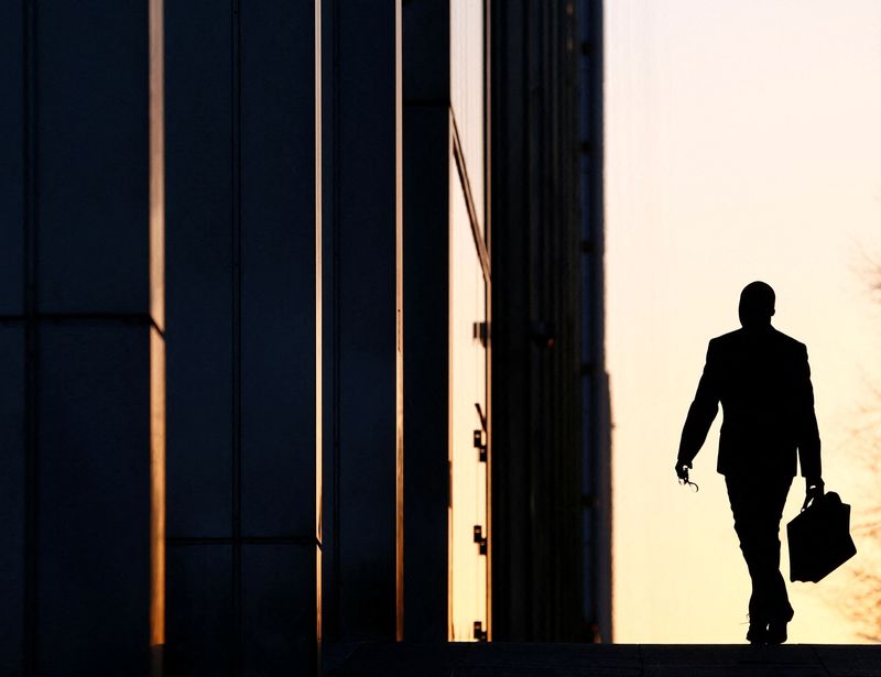 &copy; Reuters. FILE PHOTO: A worker arrives at his office in the Canary Wharf business district in London Feb. 26, 2014./File Photo