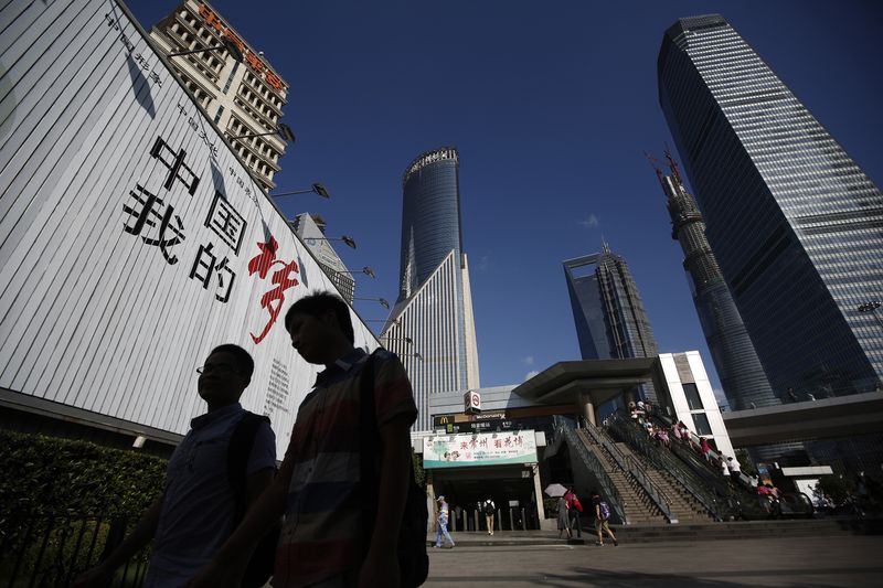 © Reuters. أشخاص يسيرون أمام لوحة إعلانية في حي بودونج المالي بمدينة شنغهاي الصينية في صورة من أرشيف رويترز .  
