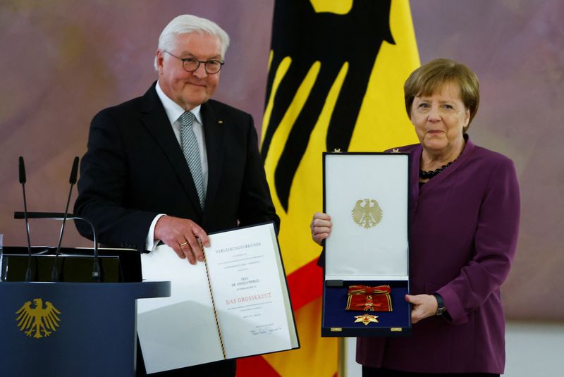 &copy; Reuters.   ドイツのメルケル前首相は１７日、国家元首である大統領以外に与えられる最高位の功労勲章を受章した。写真はドイツ・ベルリンで行われた式典で大統領が功労勲章をメルケル氏に授与