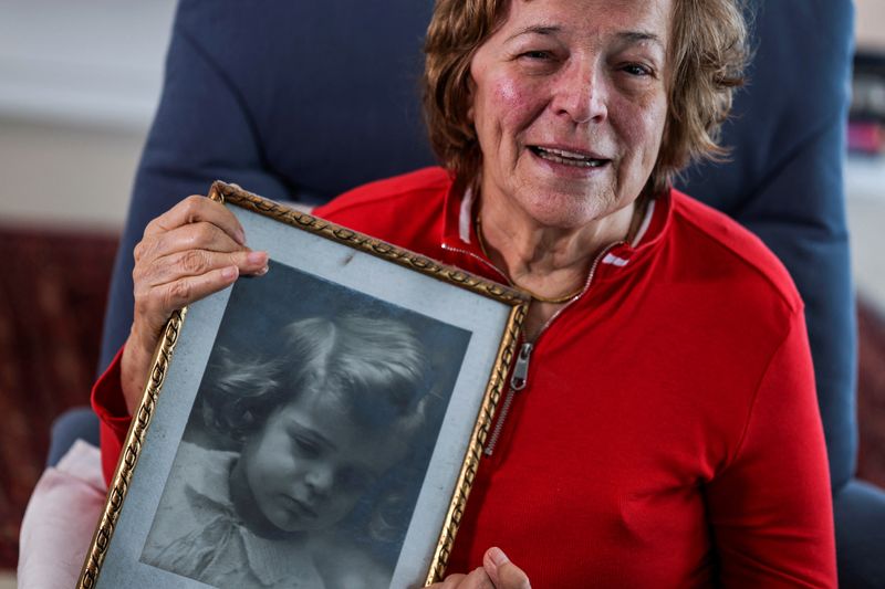 &copy; Reuters. Esther Paran, 79, a Holocaust survivor from Hungary holds up a picture from her childhood, from her living room in Tel Aviv, Israel, April 13, 2023. REUTERS/Nir Elias