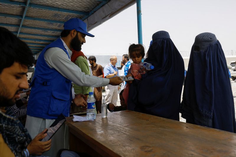 &copy; Reuters. A displaced Afghan woman receives cash aid from a WSTA employee at a cash aid distribution centre for displaced people in Kabul, Afghanistan, July 28, 2022. REUTERS/Ali Khara/File Photo