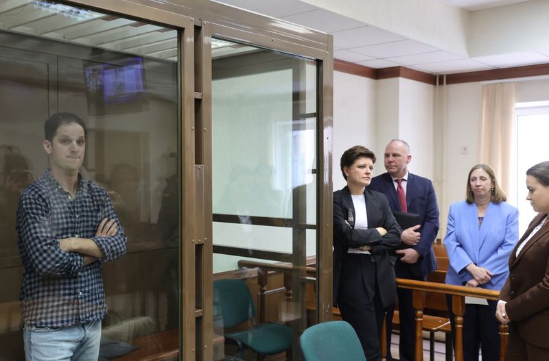 © Reuters. Wall Street Journal reporter Evan Gershkovich, who was detained in March while on a reporting trip and charged with espionage, stands behind a glass wall of an enclosure for defendants, while U.S. Ambassador to Russia Lynne Tracy and lawyers Tatyana Nozhkina and Maria Korchagina appear in a courtroom before a hearing to consider an appeal against Gershkovich's detention, in Moscow, Russia, April 18, 2023. REUTERS/Yulia Morozova