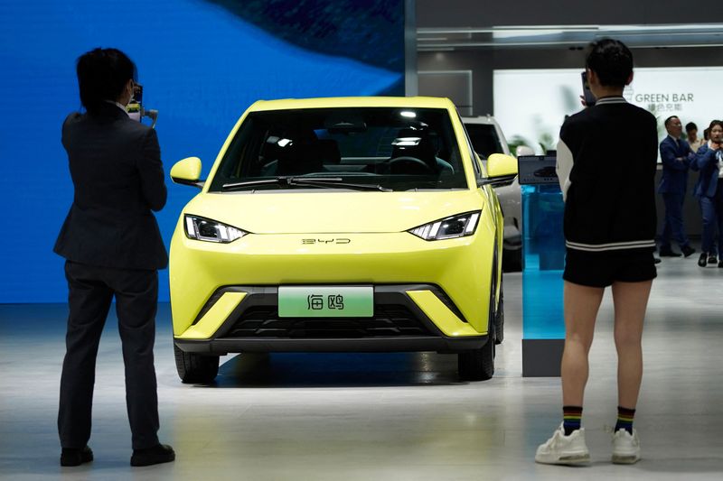 © Reuters. People use their phones in front of the BYD Seagull that is displayed at the Auto Shanghai show, in Shanghai, China April 19, 2023. REUTERS/Aly Song