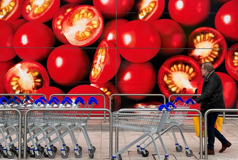 &copy; Reuters. FILE PHOTO: A shopper walks next to a photographic depiction of tomatoes on a Tesco supermarket as Britain experiences a seasonal shortage of some fruit and vegetables, in London, Britain, February 26, 2023. REUTERS/Toby Melville/File Photo