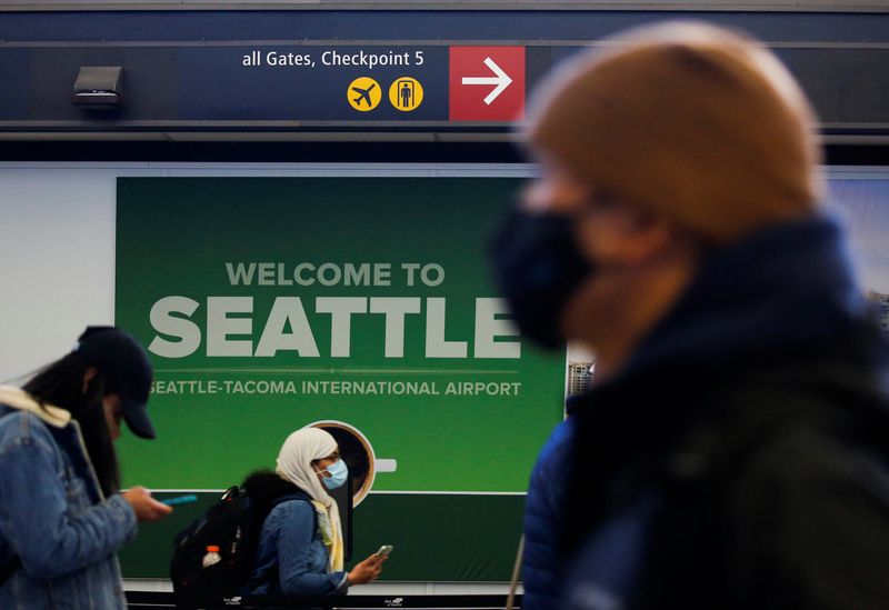 © Reuters. FILE PHOTO: People stand in front of a welcome sign at a security checkpoint at Seattle-Tacoma International Airport in SeaTac, Washington, U.S. April 12, 2021.  REUTERS/Lindsey Wasson