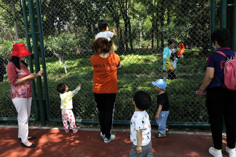 &copy; Reuters. FILE PHOTO: Children play next to adults at a park in Beijing, China June 1, 2021. REUTERS/Tingshu Wang