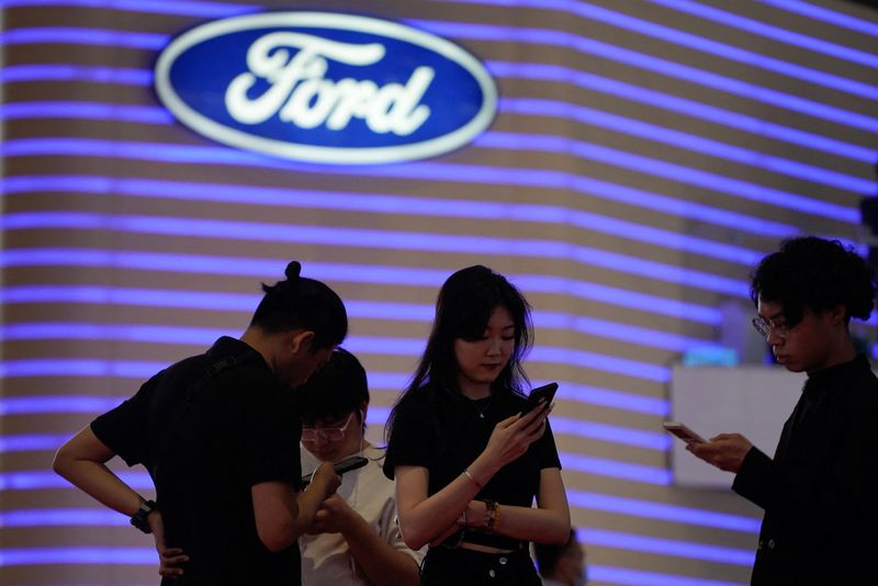 &copy; Reuters. FILE PHOTO: People stand near a logo of Ford at the Auto Shanghai show, in Shanghai, China April 18, 2023. REUTERS/Aly Song