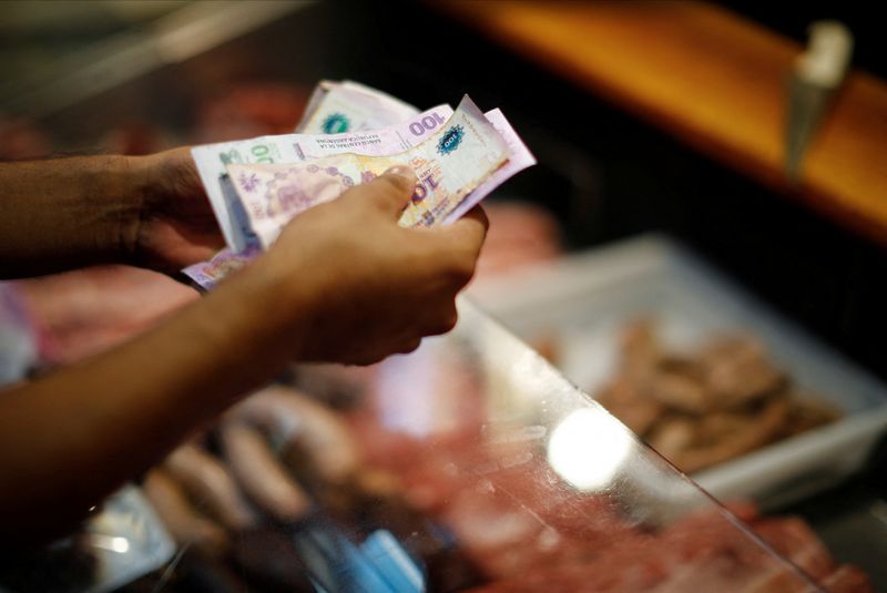 &copy; Reuters. FILE PHOTO: A customer pays for pork meat in a local market, as Argentina's annual inflation rate tore past 100% in February, the country's statistics agency said on Tuesday, the first time it has hit triple figures since a period of hyperinflation in 199