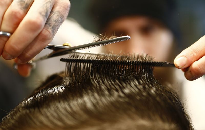 &copy; Reuters. Alex 'Torreto' Vellios, un coiffeur d'origine grecque de 26 ans, se concentre sur le coiffage d'un client dans son salon de coiffure de Torreto à Francfort. /Photo prise le 6 janvier 2015/REUTERS/Kai Pfaffenbach 