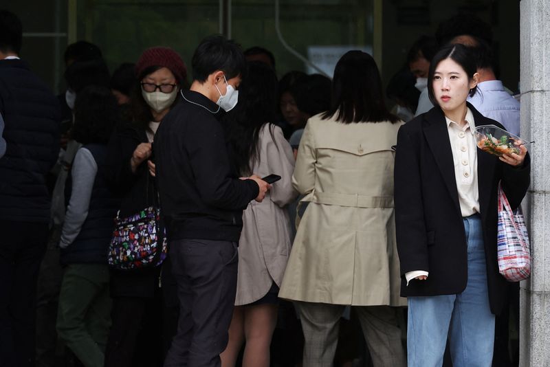 &copy; Reuters. FILE PHOTO: A woman eats a salad in front of office workers looking at their mobile phones to check the local online banking app Toss at Seoul Museum of Art during a lunch break in Seoul, South Korea, April 13, 2023.   REUTERS/Kim Hong-Ji