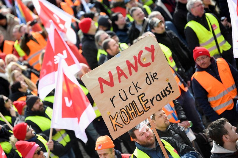 &copy; Reuters. Un manifestante tiene un cartello con la scritta "Nancy (Nancy Feser, ministro degli Interni tedesco) dacci i soldi" mentre alcune persone manifestano davanti al "Landungsbruecken" al porto durante uno sciopero nazionale indetto dal sindacato tedesco Verd
