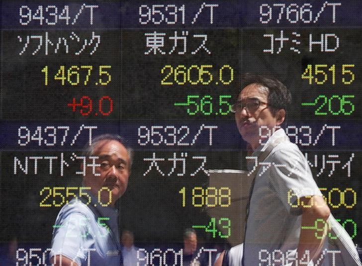 &copy; Reuters. Imagen de archivo de peatones reflejados en una pantalla con cotizaciones bursátiles en una correduría de Tokio, Japón.
