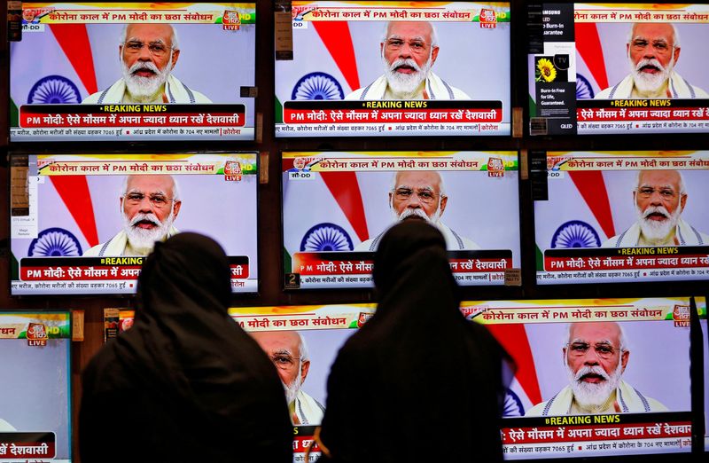 &copy; Reuters. FILE PHOTO: Women watch Indian Prime Minister Narendra Modi address the nation amid the spread of the coronavirus disease (COVID-19), on TV screens inside a showroom in Ahmedabad, India, June 30, 2020. REUTERS/Amit Dave