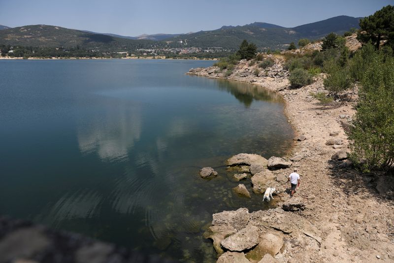 &copy; Reuters. FOTO DE ARCHIVO: Un hombre y su perro caminan junto a la presa de Navacerrada, al norte de Madrid, mientras los niveles de agua permanecen bajos durante una ola de calor en España, 31 de julio de 2022. REUTERS/Isabel Infantes