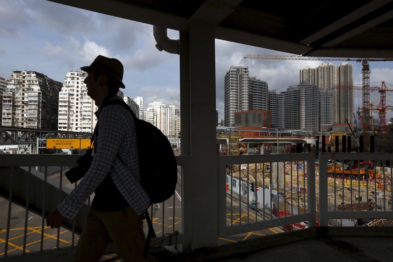 &copy; Reuters. FILE PHOTO: A man walks on a footbridge as 45-year-old residential flats (L), the latest luxury homes (R) and a construction site are seen in the background, in West Kowloon, Hong Kong, China July 2, 2015.   REUTERS/Bobby Yip