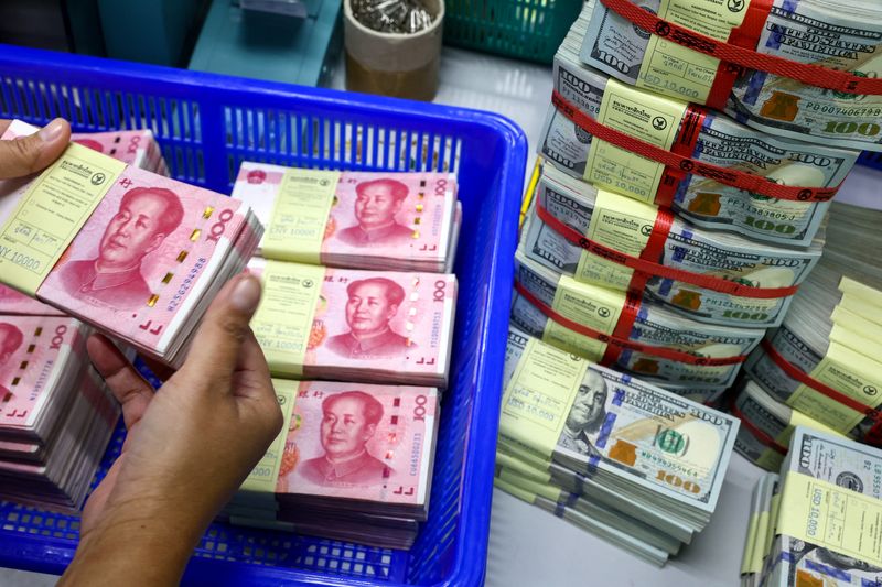 &copy; Reuters. FILE PHOTO: A bank employee count China’s renminbi (RMB) or yuan notes next to U.S. dollar notes at a Kasikornbank in Bangkok, Thailand, January 26, 2023. REUTERS/Athit Perawongmetha