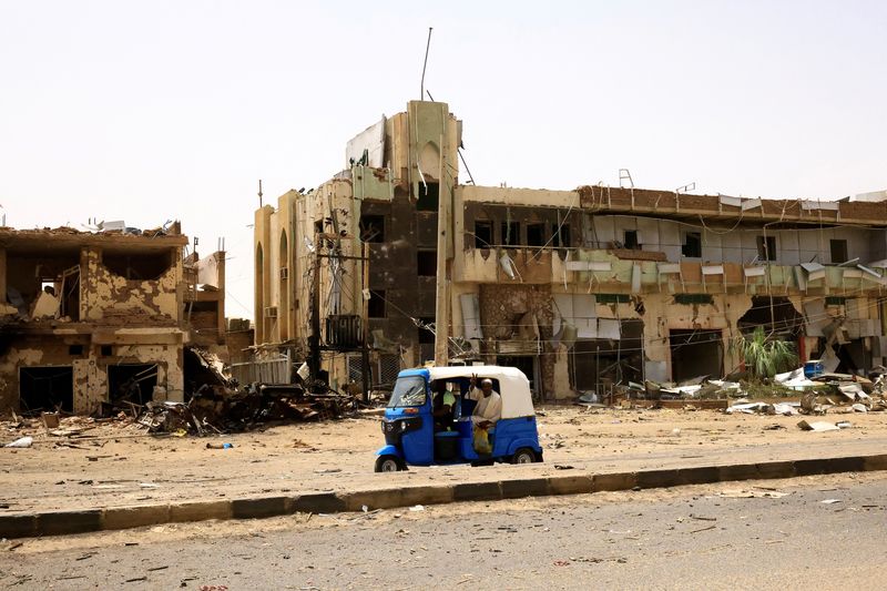 &copy; Reuters. سودانيون يمرون بالقرب من سيارات ومبان لحقت بها أضرار في السوق المركزية خلال اشتباكات بين قوات الدعم السريع شبه العسكرية والجيش السوداني في 