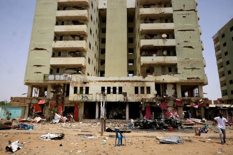 &copy; Reuters. A man walks near a damaged car and buildings at the central market during clashes between the paramilitary Rapid Support Forces and the army in Khartoum North, Sudan April 27, 2023. REUTERS/ Mohamed Nureldin Abdallah