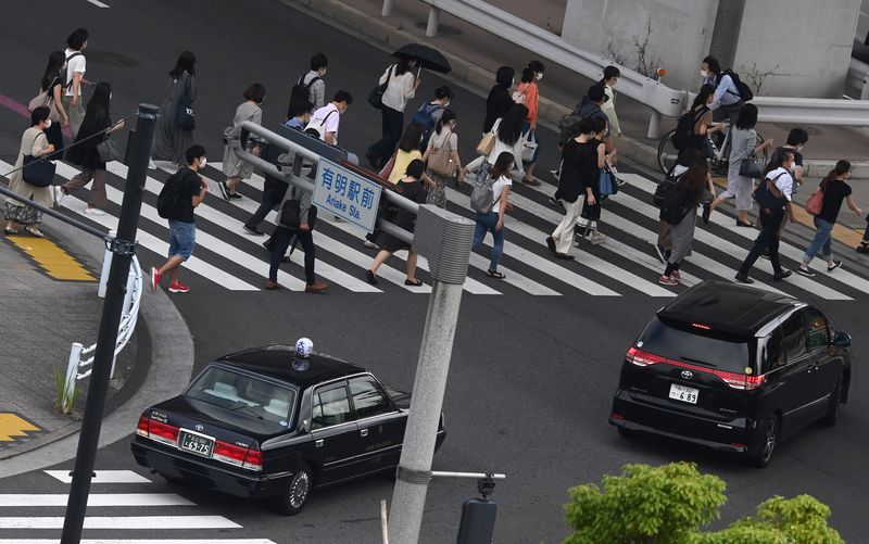 &copy; Reuters. FILE PHOTO: Workers cross a road during the morning rush hour, ahead of the Tokyo 2020 Olympic Games that have been postponed to 2021 due to the coronavirus disease (COVID-19) pandemic, in Tokyo, Japan, July 15, 2021. REUTERS/Toby Melville