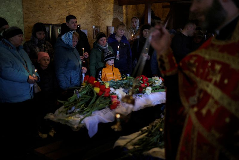 © Reuters. Parents, Inna and Dimitri, along with their son, Mikhail, pay respects during the funeral of their two children, Sofia and Kyrylo, who officials said were killed on Friday by a Russian missile strike, amid Russia's attack on Ukraine, in the town of Uman, Cherkasy region, Ukraine April 30, 2023. REUTERS/Carlos Barria