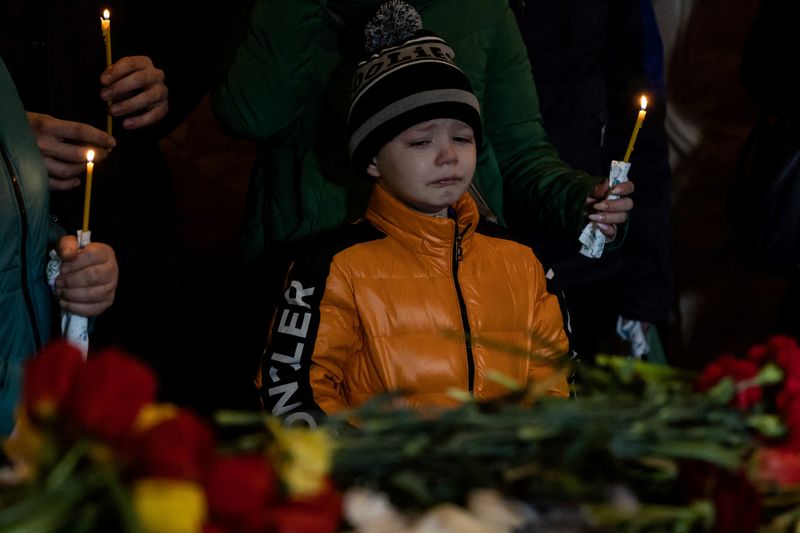 © Reuters. Mikhail looks at the caskets of his sister and brother, Sofia and Kyrylo, during their funeral after Friday's Russian missile strike destroyed his apartment building where his family lived, amid Russia's attack on Ukraine, in the town of Uman, Cherkasy region, Ukraine April 30, 2023. REUTERS/Carlos Barria    