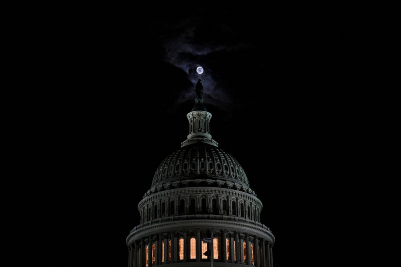 © Reuters. FILE PHOTO: The moon is seen behind the dome of the U.S. Capitol building at night in Washington, DC, U.S., February 16, 2022. REUTERS/Jon Cherry  
