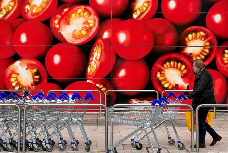 © Reuters. FILE PHOTO: A shopper walks next to a photographic depiction of tomatoes on a Tesco supermarket as Britain experiences a seasonal shortage of some fruit and vegetables, in London, Britain, February 26, 2023. REUTERS/Toby Melville