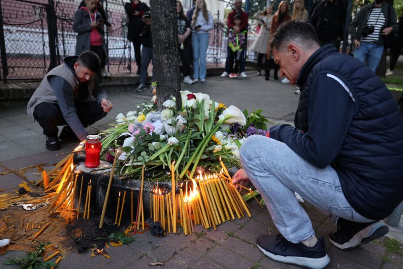 © Reuters. People light candles near a school after a boy, 13, opened fire on other students and staff at the school in Belgrade, Serbia, May 3, 2023. REUTERS/Antonio Bronic