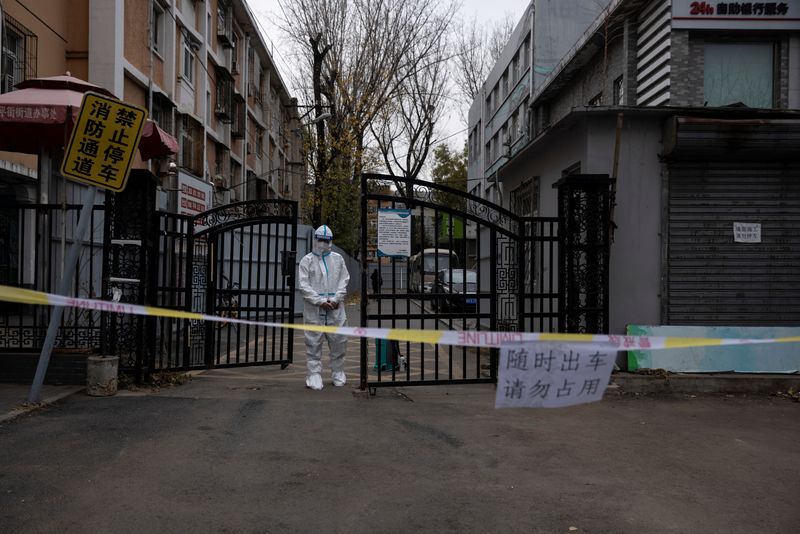 &copy; Reuters. FILE PHOTO: An epidemic-prevention worker in a protective suit stands guard at the gate of a residential compound as coronavirus disease (COVID-19) outbreaks continue in Beijing, China November 28, 2022. REUTERS/Thomas Peter