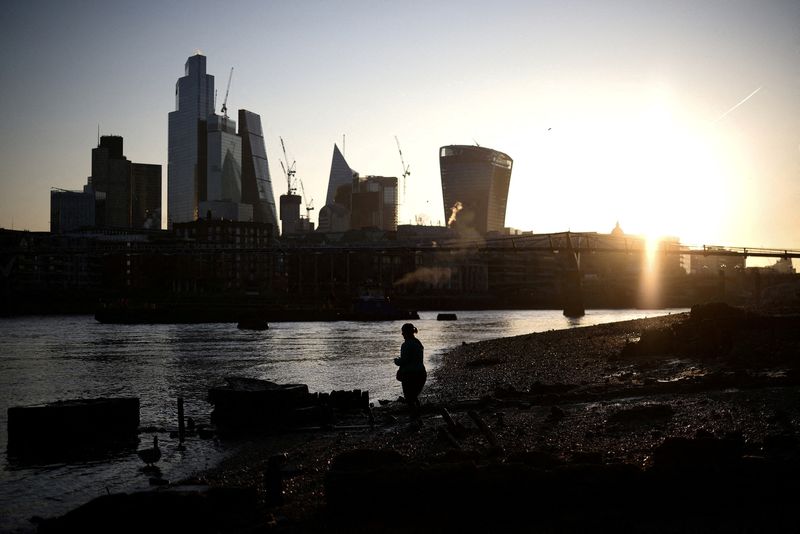 © Reuters. FILE PHOTO: A person stands on the bank of the River Thames during sunrise, with the City of London financial district in the background, in London, Britain, April 4, 2023. REUTERS/Henry Nicholls