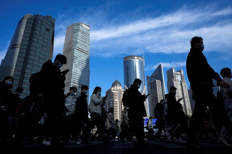 &copy; Reuters. FILE PHOTO: People cross a street near office towers in the Lujiazui financial district, ahead of the National People's Congress (NPC), in Shanghai, China, February 28, 2023. REUTERS/Aly Song   