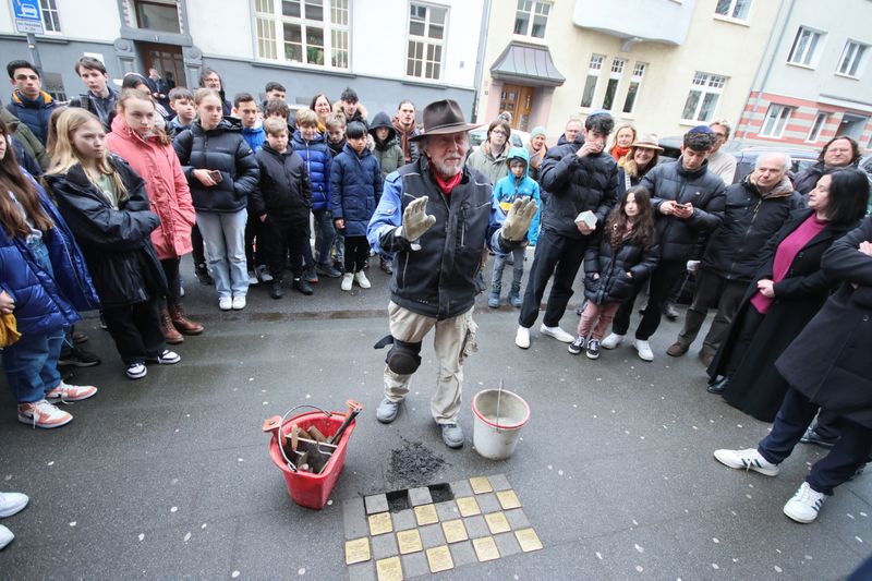 &copy; Reuters. FILE PHOTO: Stumbling stones (Stolpersteine) artist Gunter Demnig is surrounded by relatives of Holocaust victims and pupils of the Deutzer Gymnasium Schaurtestrasse during a stone laying ceremony for a former teacher and a former pupil of the school in C