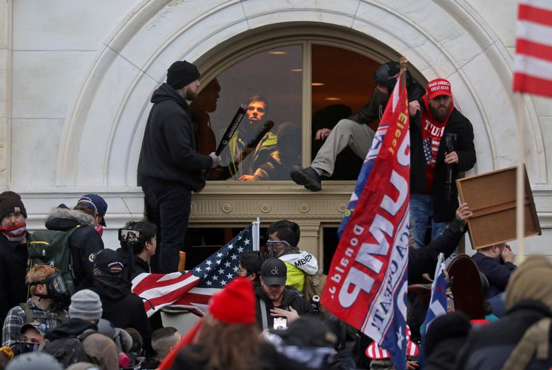 © Reuters. FILE PHOTO: A mob of supporters of U.S. President Donald Trump climb through a window they broke as they storm the U.S. Capitol Building in Washington, U.S., January 6, 2021. REUTERS/Leah Millis/File Photo