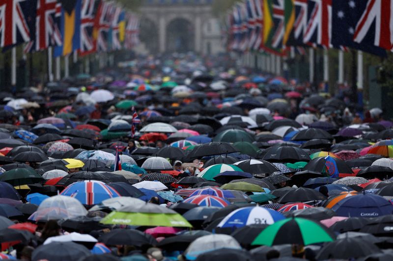 © Reuters. منظر عام لعشرات من الناس يحتمون بالمظلات من المطر في شارع ذا مول في لندن أثناء متابعتهم  الاحتفالات بتتويج الملك تشارلز  يوم السبت . تصوير : كلودا كيلكوين - رويترز . 