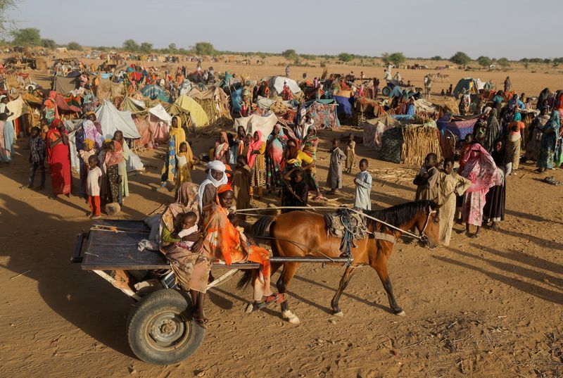 © Reuters. FILE PHOTO: Sudanese refugees who fled the violence in their country, ride a cart as they pass other refugees standing beside makeshift shelters near the border between Sudan and Chad in Koufroun, Chad May 6, 2023. REUTERS/Zohra Bensemra/File Photo