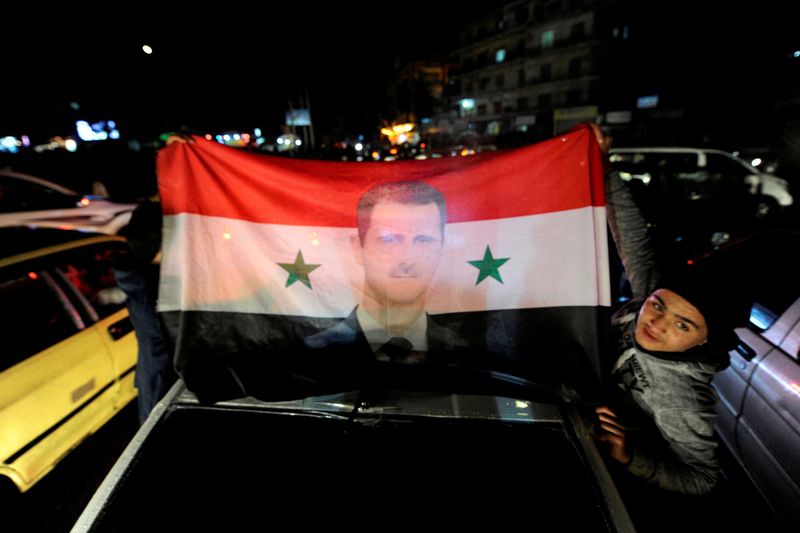 © Reuters. أنصار الرئيس السوري بشار الأسد يرفعون العلم السوري وعليه صورته. الصورة من أرشيف رويترز 