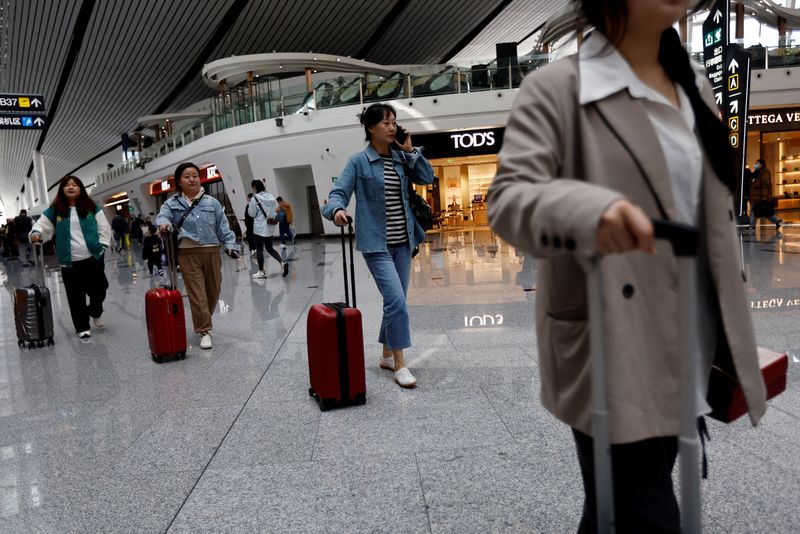 © Reuters. FILE PHOTO: Travellers walk with their suitcases at Beijing Daxing International Airport in Beijing, China April 24, 2023. REUTERS/Tingshu Wang/File Photo