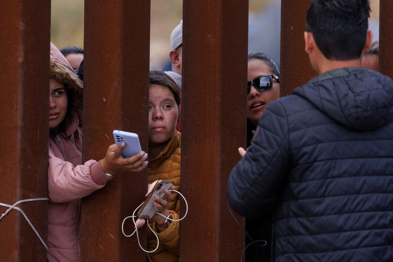 © Reuters. Migrants reach out from the border fence to try and get their phones charged while stuck between primary and secondary border fences as the United States prepares to lift COVID-19 era Title 42 restrictions that have blocked migrants at the U.S.-Mexico border from seeking asylum since 2020 near San Diego, California, U.S., May 10, 2023. REUTERS/Mike Blake