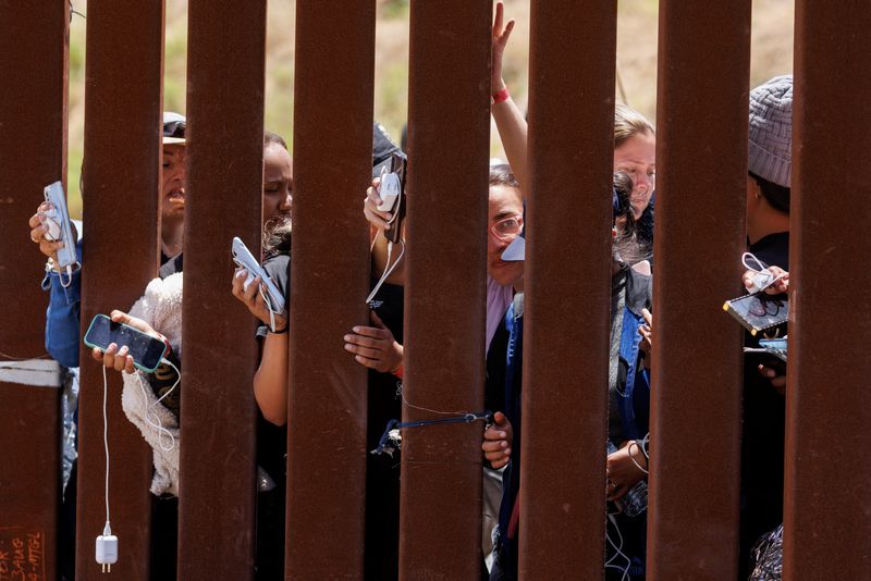 &copy; Reuters. Migrants hope to get their phones charged by aid workers while they wait between the primary and secondary border fences as the United States prepares to lift COVID-19 era Title 42 restrictions that have blocked migrants at the U.S.-Mexico border from see