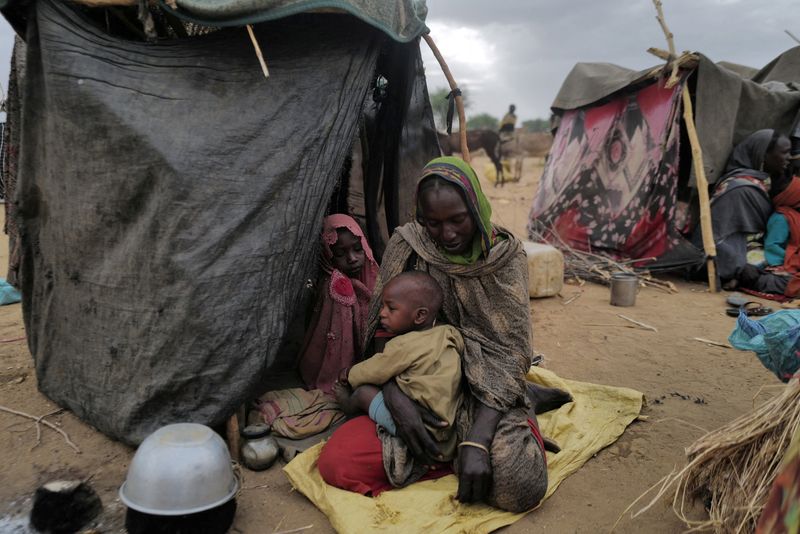 &copy; Reuters. لاجئة سودانية فرت من العنف في إقليم دارفور تجلس مع طفلها بجوار مأوى مؤقت بالقرب من الحدود بين السودان وتشاد في كفرون يوم الخميس. تصوير: زهرة 