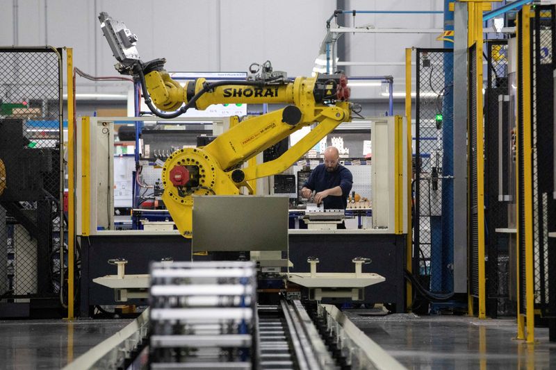 &copy; Reuters. FILE PHOTO: A factory worker works on an aircraft part, as the robot arm of an automated five-axis cell operates autonomously nearby, at Abipa Canada, in Boisbriand, Quebec, Canada May 10, 2023. REUTERS/Evan Buhler/File Photo