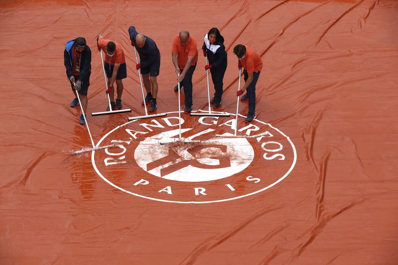 &copy; Reuters. Funcionário tiram água de lona protetora após chuva paralisar partidas do torneio de Roland Garros, em Paris
04/06/2021 REUTERS/Christian Hartmann