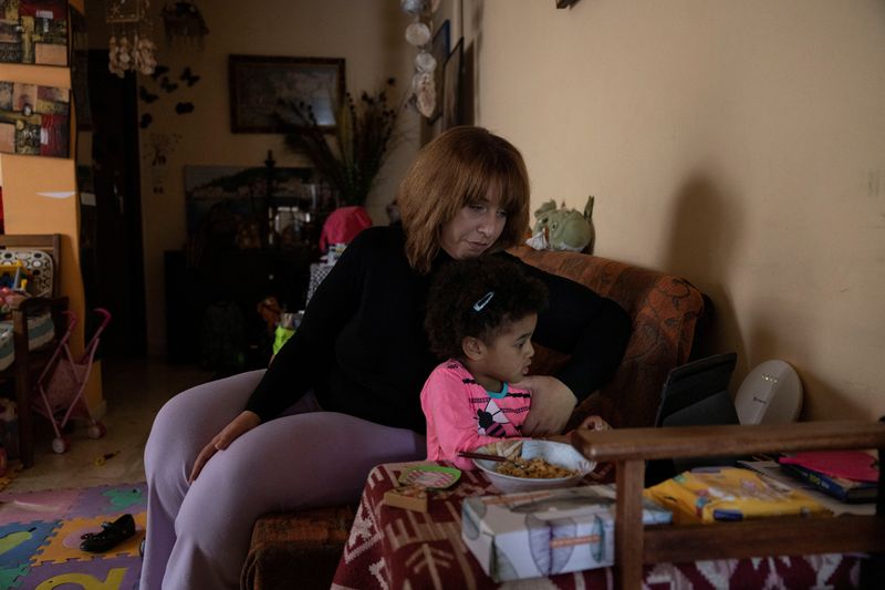 &copy; Reuters. Niki Klaoudatou and her child Amelia watch a video at their home in Athens, Greece May 5, 2023. REUTERS/Stelios Misinas